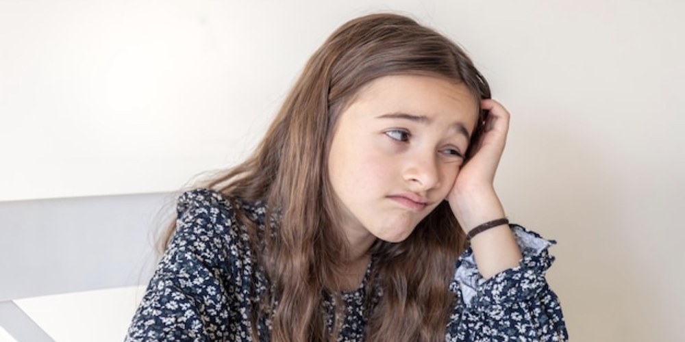 A preteen sitting quietly, looking thoughtful and withdrawn